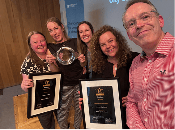 Some (5) of the planning team standing and smiling holding the three awards.