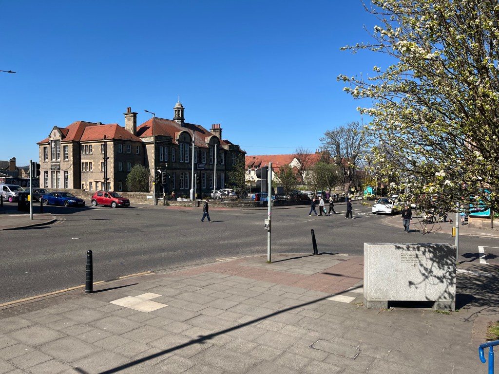 Drum Street crossroads, Gilmerton - a junction with no cars on it on a sunny day with the community centre in the background.