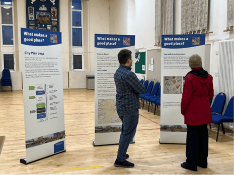 People viewing City Plan 2040 consultation boards in a community hall.